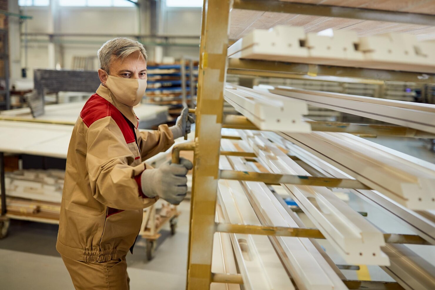 manual-worker-with-face-mask-moving-rack-with-processed-wood-carpentry-workshop_637285-11729